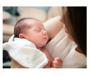 newborn sleep tips - a person with shoulder length brown hair holding a newborn with dark hair in a white sleeper