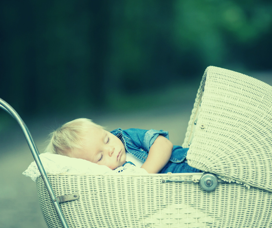 motion sleep - a photo of a baby sleeping in an old fashioned pram. Blonde hair and a blue t-shirt