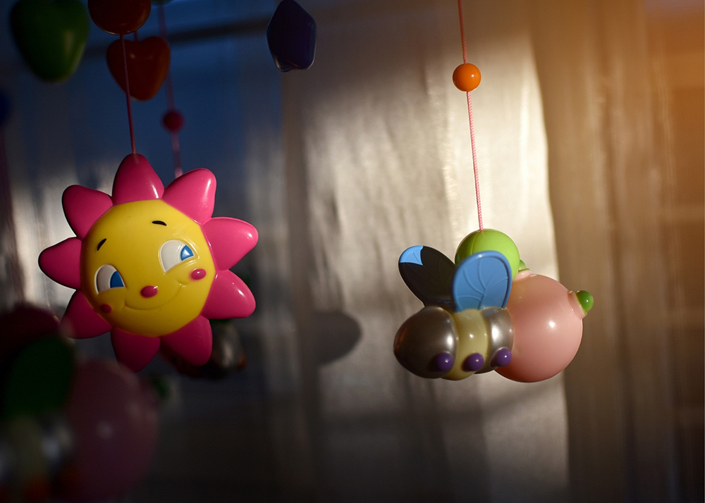 Good sleep - a photo of a dark room with a baby mobile lit up a bit. A yellow sun with pink rays.