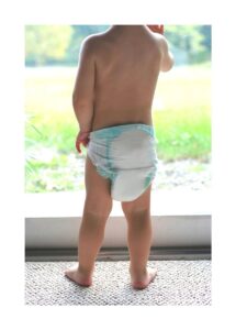 Child at the window wearing a diaper. Facing out, not the camera