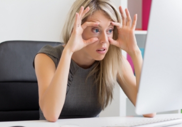 Woman trying to hold her eyes open in front of computer monitor