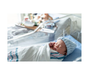 partner - photo of a baby in the hospital wrapped in a blanket with a blue knit hat.