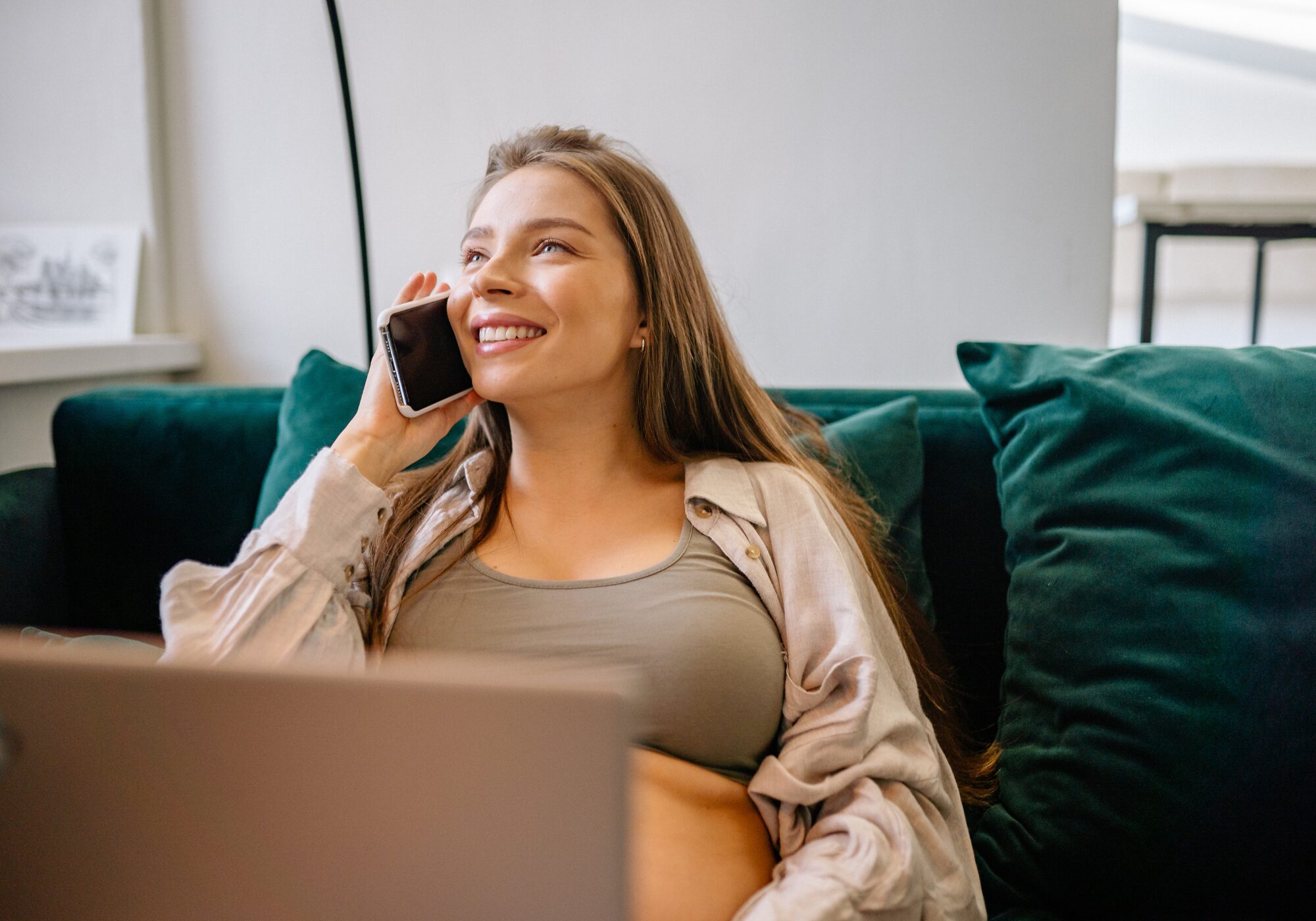 Listening - a person on the phone with long blown hair with a laptop on their lap. The person is smiling.